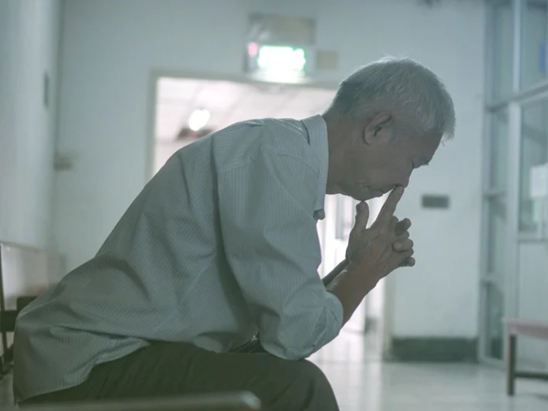 A man sitting and leaning forward looking distressed