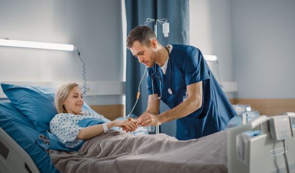 A patient in a hospital bed receiving treatment from a nurse