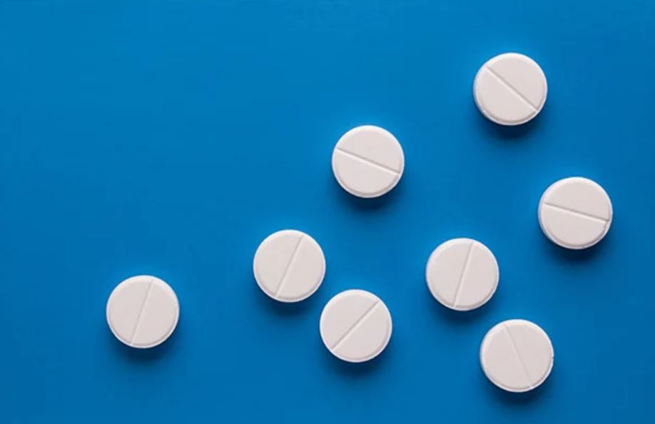 eight round white tablets sitting on top of a light blue surface