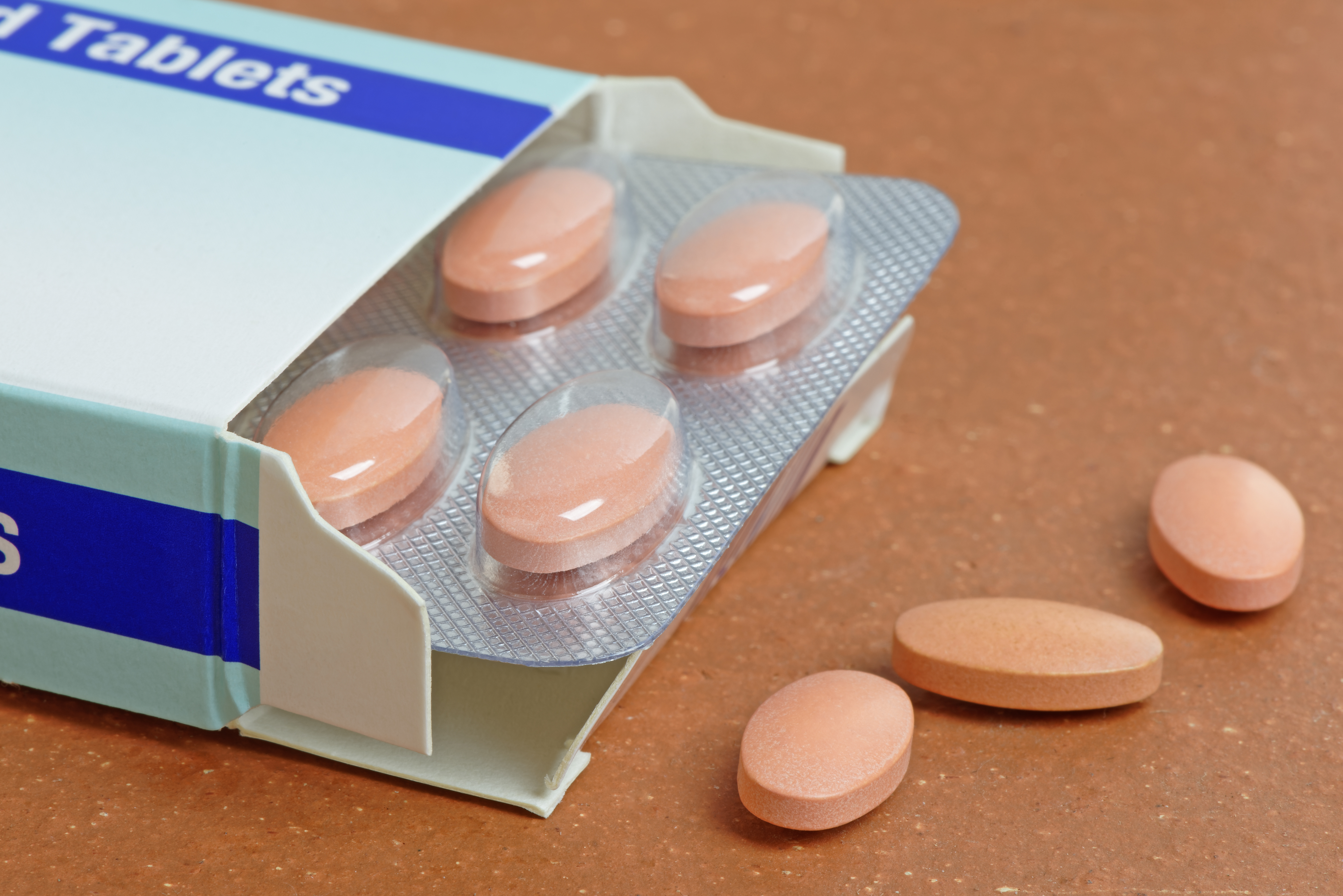 a packet of orange oval shaped tablets sitting on a brown table