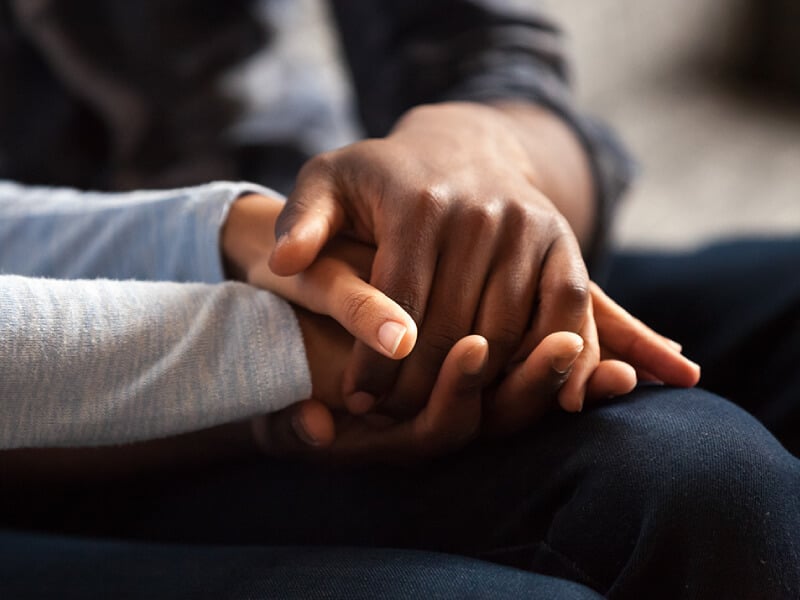 Two people's hands clasped together