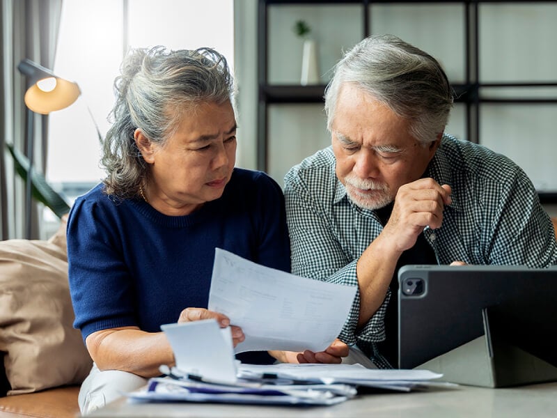Two elderly people looking at bills and paperwork