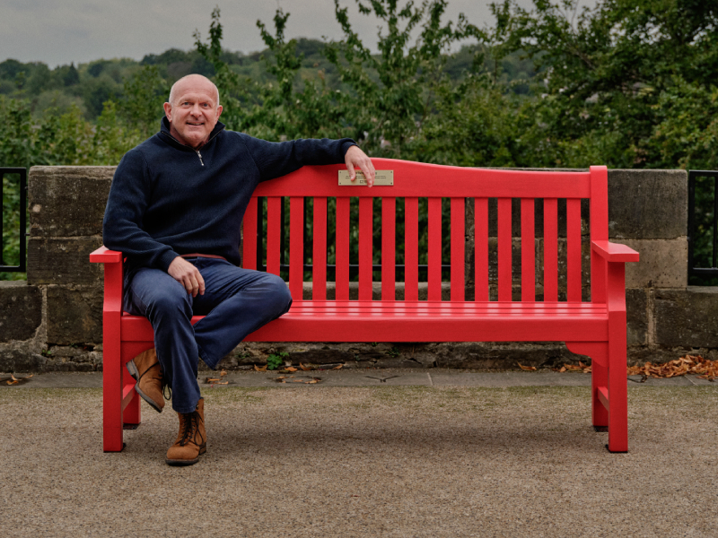 Dean sat on a red bench smiling