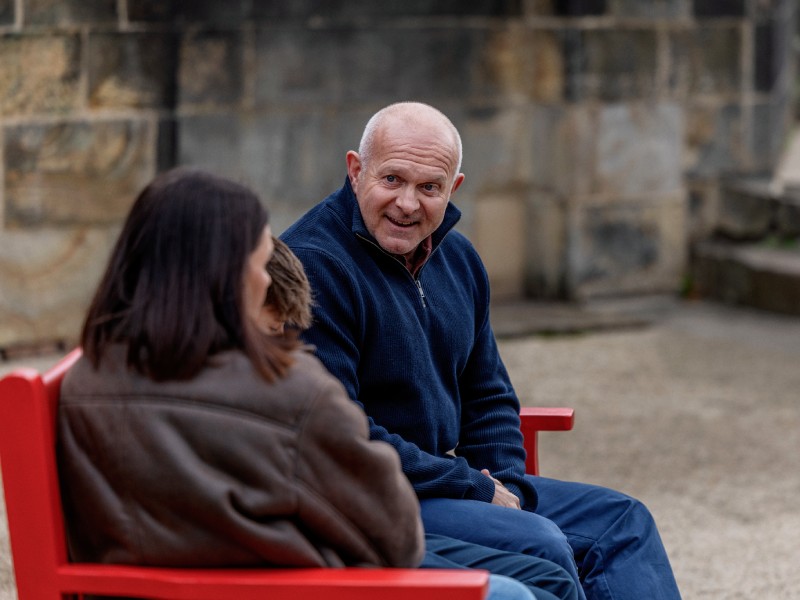 Dean sat on a red bench smiling at his family