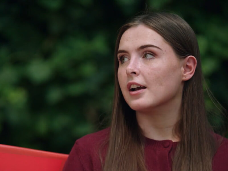 Ellie sat on a red bench talking to Dr Zachary Whinnett