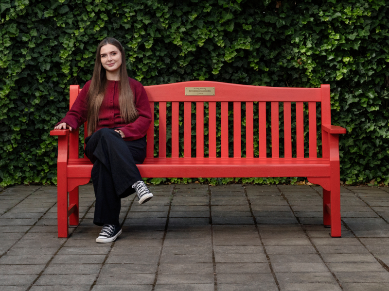 Ellie sat on a red bench smiling