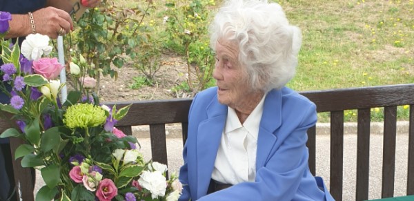 Joan on bench with flowers 