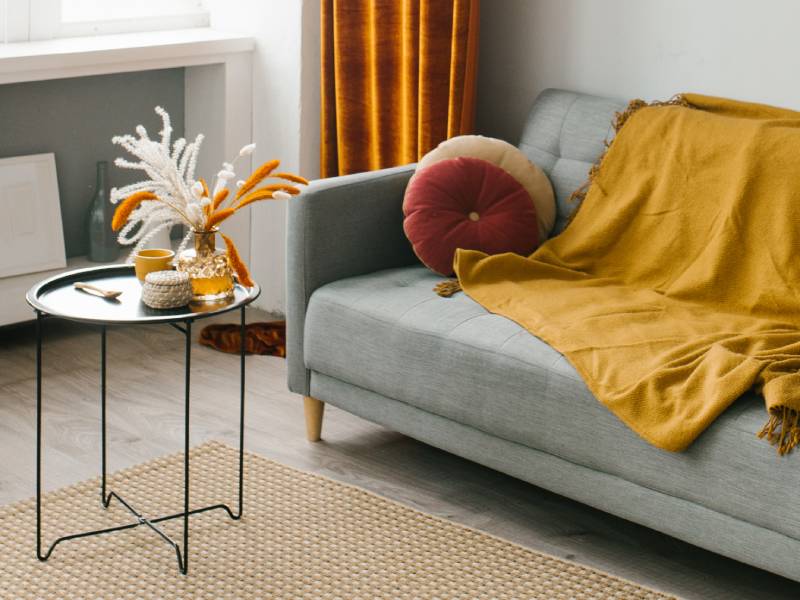 A living room sofa with a blanket draped over it and a circular coffee table