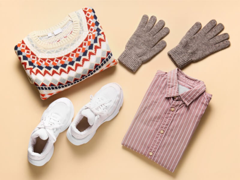 A photo of a jumper, gloves, a shirt and white trainers.
