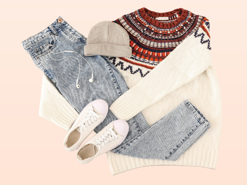 A photo of jeans, a jumper, beanie hat and white trainers.