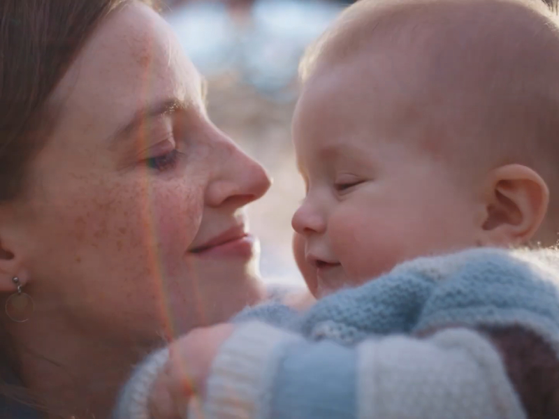 A woman holding a baby and smiling