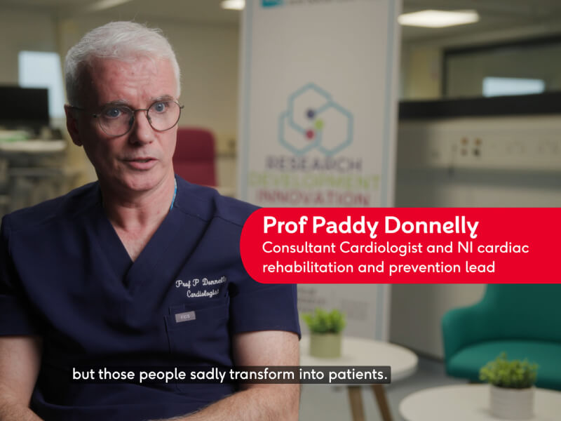 Professor Paddy Donnelly in navy scrubs sat inside an office space
