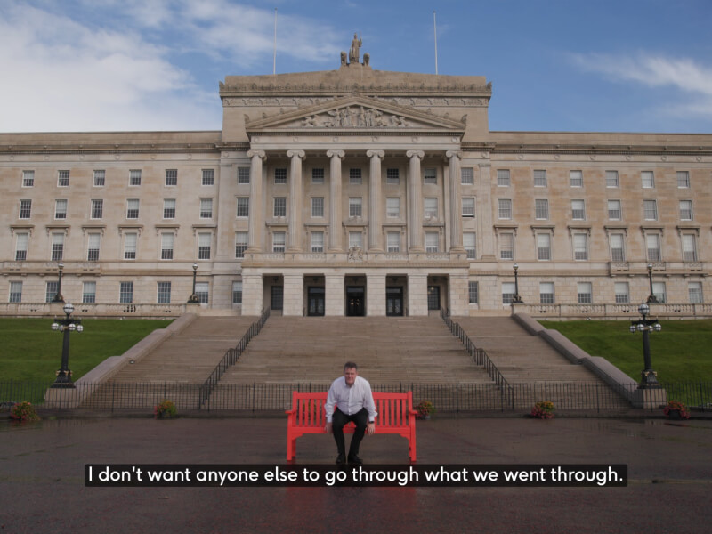 Terry sits in a red chair outside a NI building