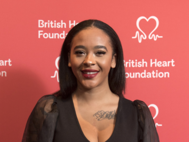 A woman smiling behind a BHF branded red backdrop