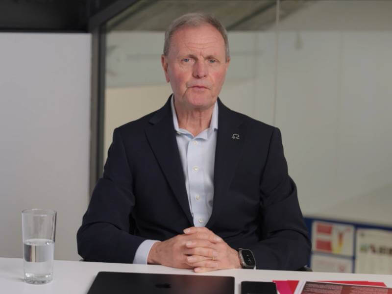 Byan Williams sitting at a white desk with his hands clasped together