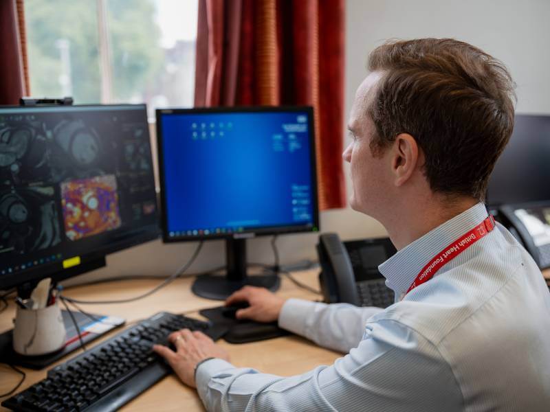 BHF-funded researcher sat at a desk looking at a computer 