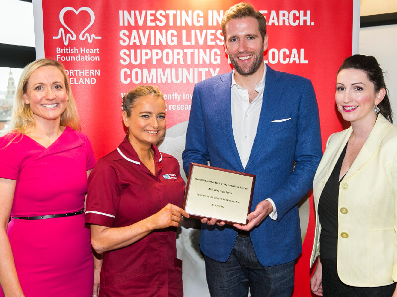Four people smiling as they accept an award 