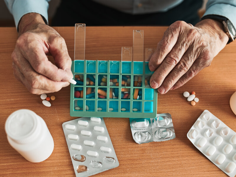 A person puts pills into a pill organiser 
