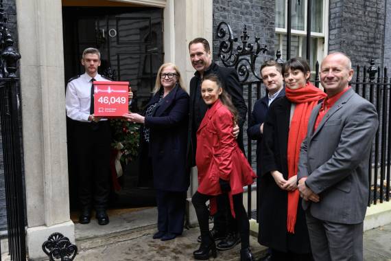 BHF staff members including the CEO Charmaine Griffiths standing outside No 10 Downing Street and holding the Hearts Need More pledge with 46000 signatures