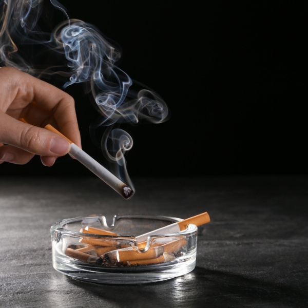 hand holding cigarette over ashtray