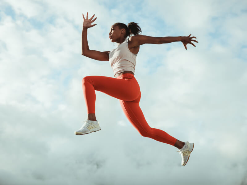 A black female athlete is leaping through the air