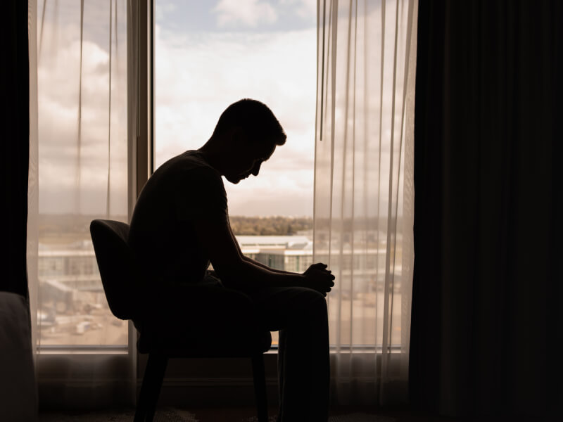 A man sits in a room in front of a window