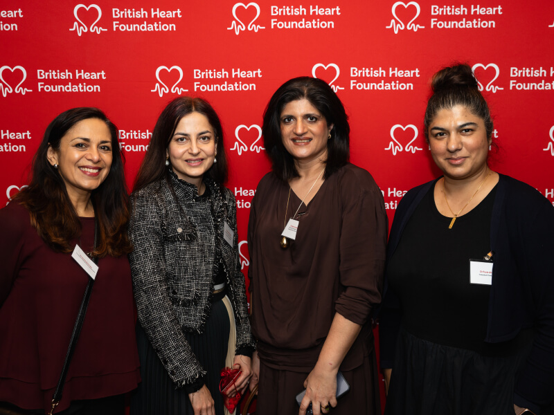 4 women pose for a photograph with a red background featuring BHF's logo