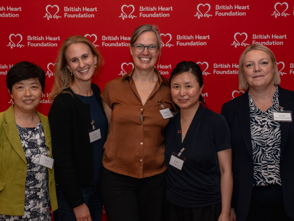 A group of attendees at the Women in Science 2026 event, smiling in front of a BHF‑branded display.