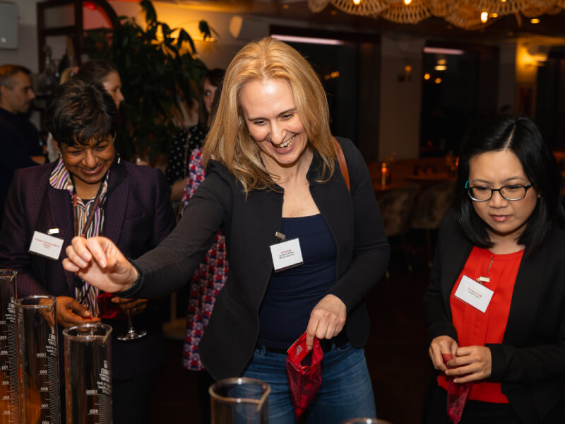 3 women stand and look at science beakers at Women in Science event