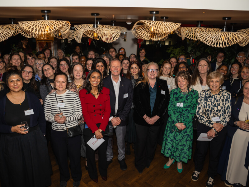Large group of attendees are gathered and smiling at Women in Science event
