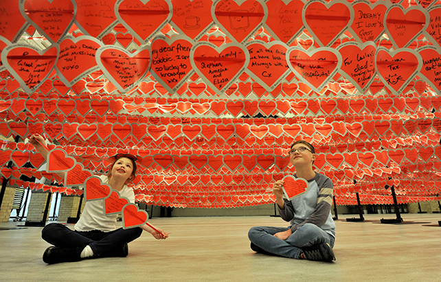 Two children affected by heart disease sit under a display of the love notes in the world record attempt