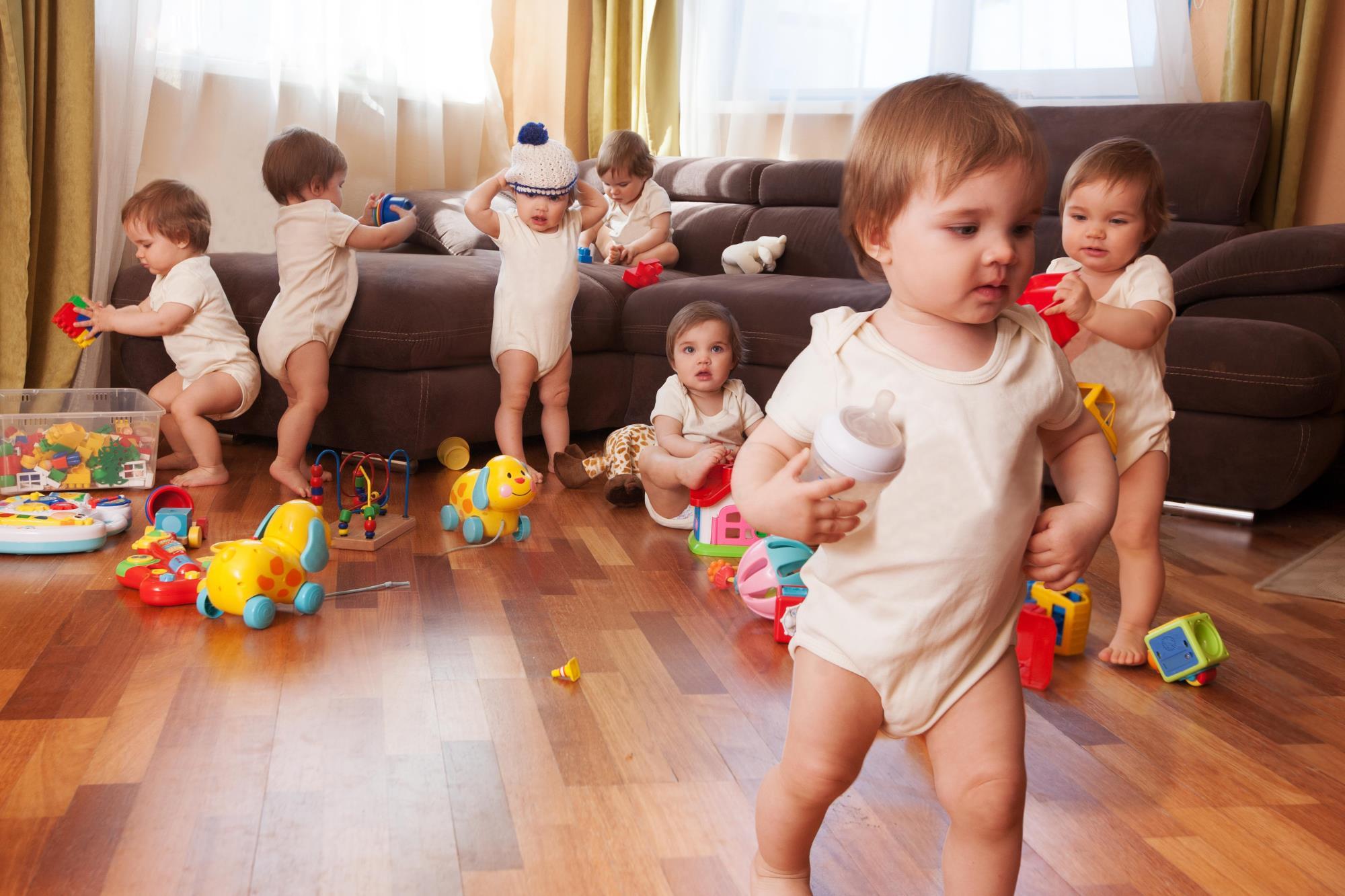 7 small children playing on a sofa with scattered toys