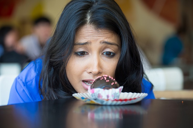 woman looking longingly at chocolate cupcake