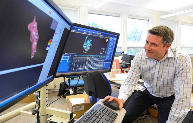 A man looking at health scans on two computer monitors
