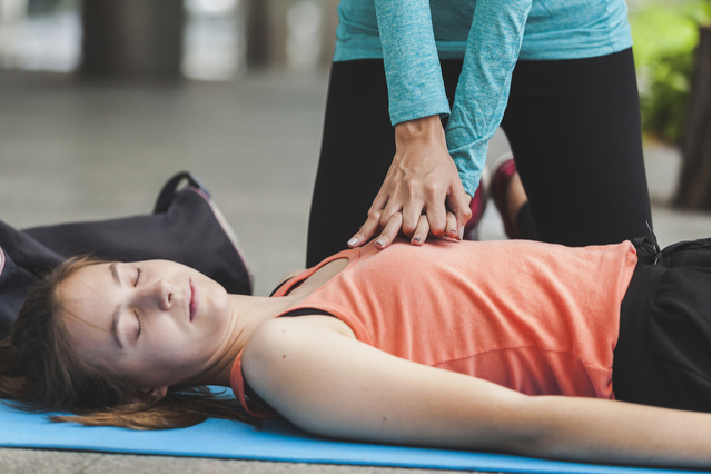 An individual performing chest presses on an unconscious woman