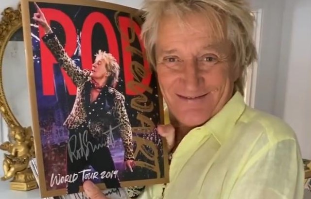 Rod Stewart holding a signed copy of a world tour programme