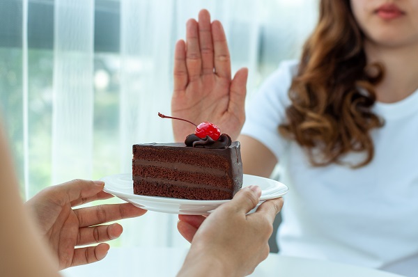 woman saying no to a slice of chocolate cake