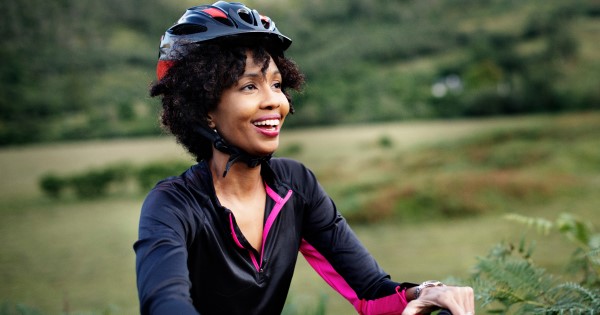 Image of a woman cycling outdoors with helmet on 