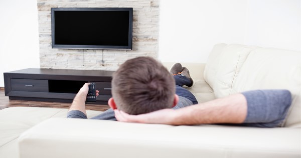A man sitting on a sofa watching television.