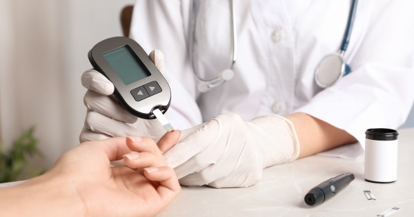 A doctor tests the blood sugar of their patient using a blood glucose monitor