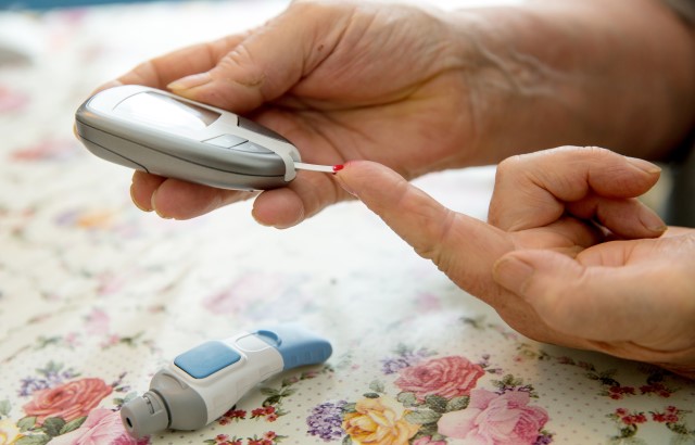 Woman checking her sugar level with a glucometer