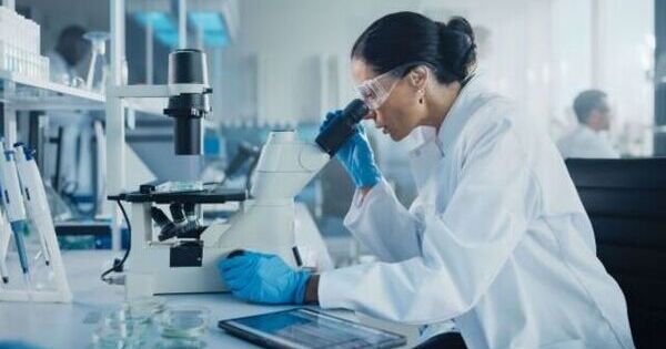 Researcher looking down microscope