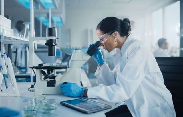 Researcher looking down microscope