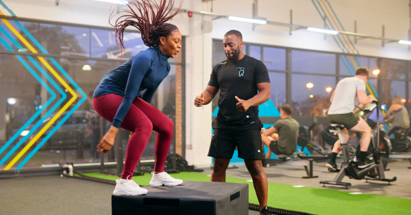 Image of a lady exercising with a member of PureGym staff watching 