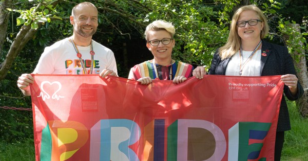 Gareth Campbell-Julian, Allison Swaine-Hughes and Charmaine Griffiths hold a BHF Pride flag.