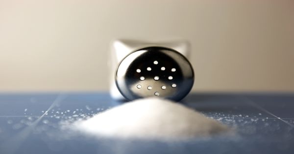 A stock image of a salt shaker on its side with a pile of salt in front of it