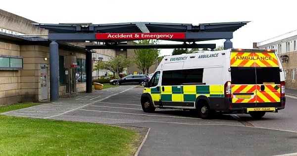 An ambulance drives into a covered porch area at an A&E department