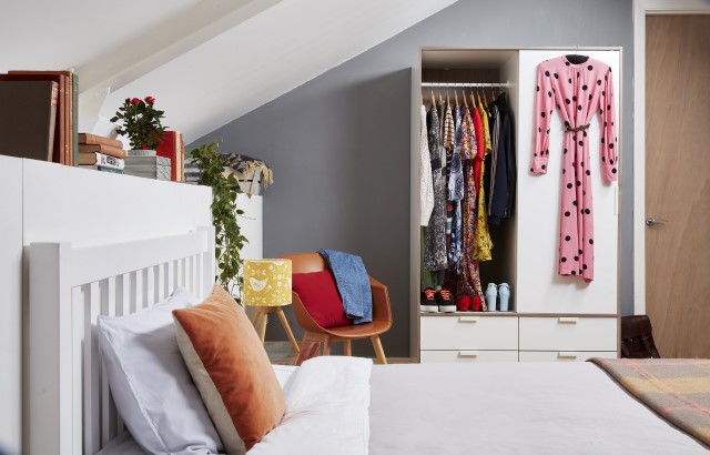 Image shows a bedroom and wardrobe full of clothes.