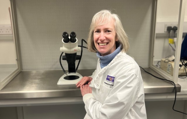 Research scientist Dr Kathryn Hentges wearing a lab coat and sitting in her laboratory