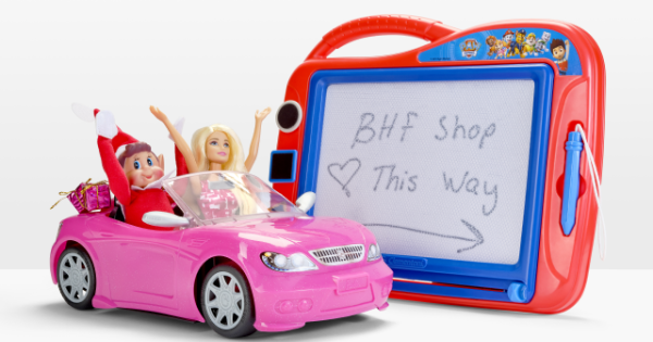 Elf and Barbie driving in a toy car with a sign pointing them towards the BHF shop.